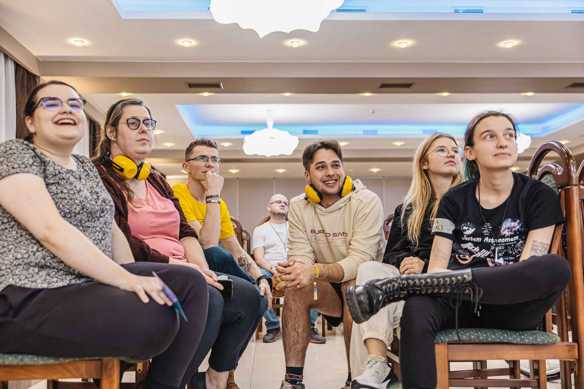 Grupa młodych osób siedzących blisko siebie.