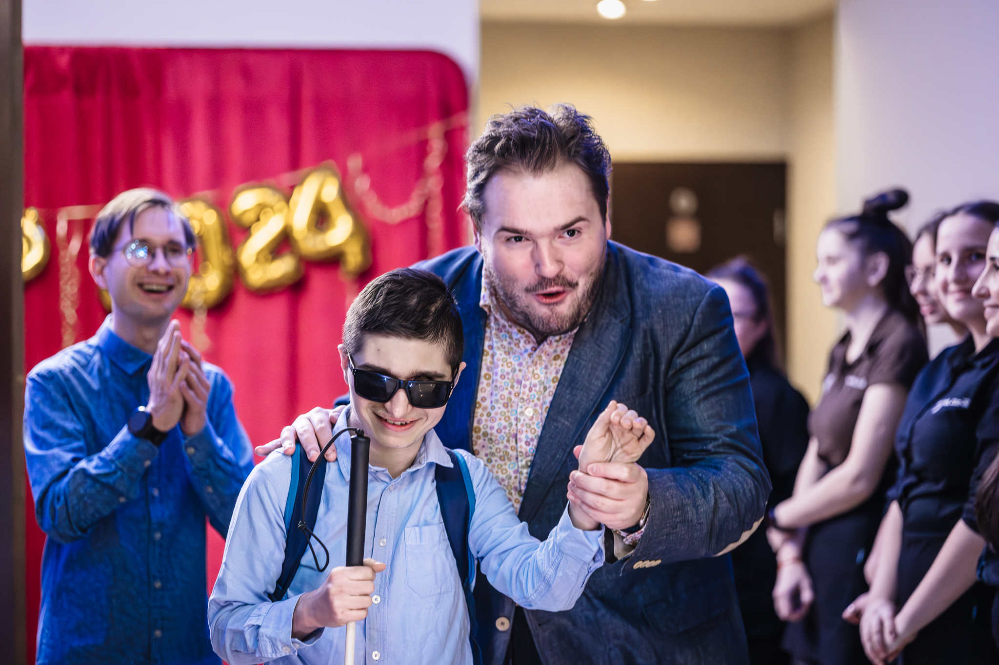 Osoba niewidoma prowadzona przez asystenta w kierunku bankietu.