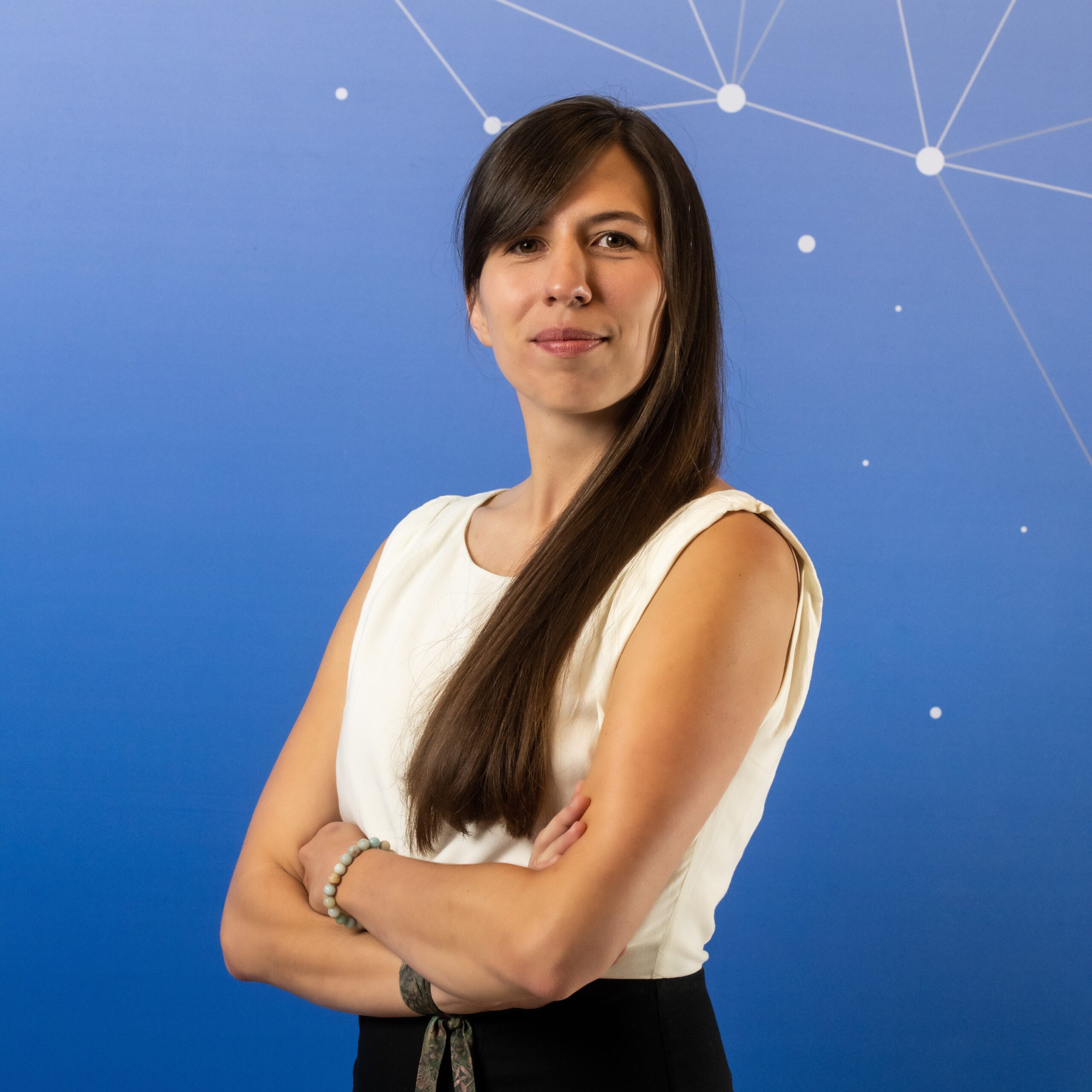 Kobieta pozująca do zdjęcia biznesowego na niebieskim tle.